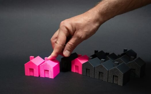A hand is pointing at a small pink house